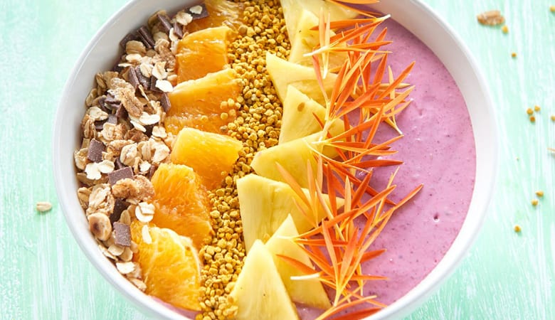 Bowl ai frutti rossi con topping di ananas, arancia rossa, polline e muesli